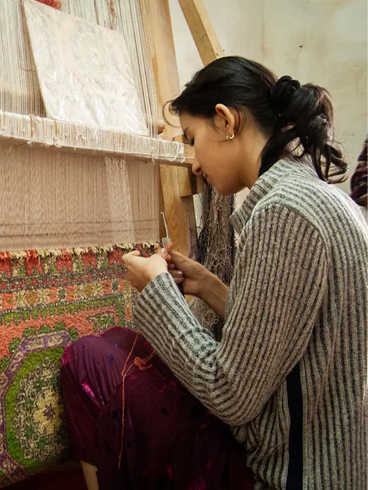 A Bhadohi weaver knotting wool by hand at a traditional loom