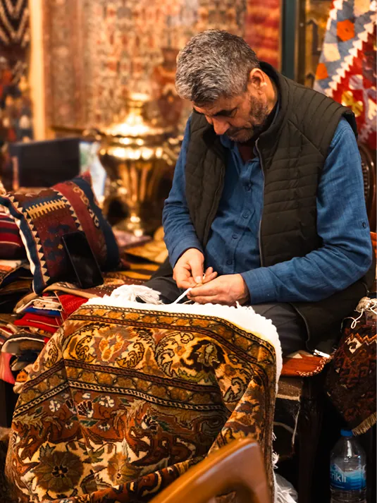Rajan carefully finishing the edge of a rug